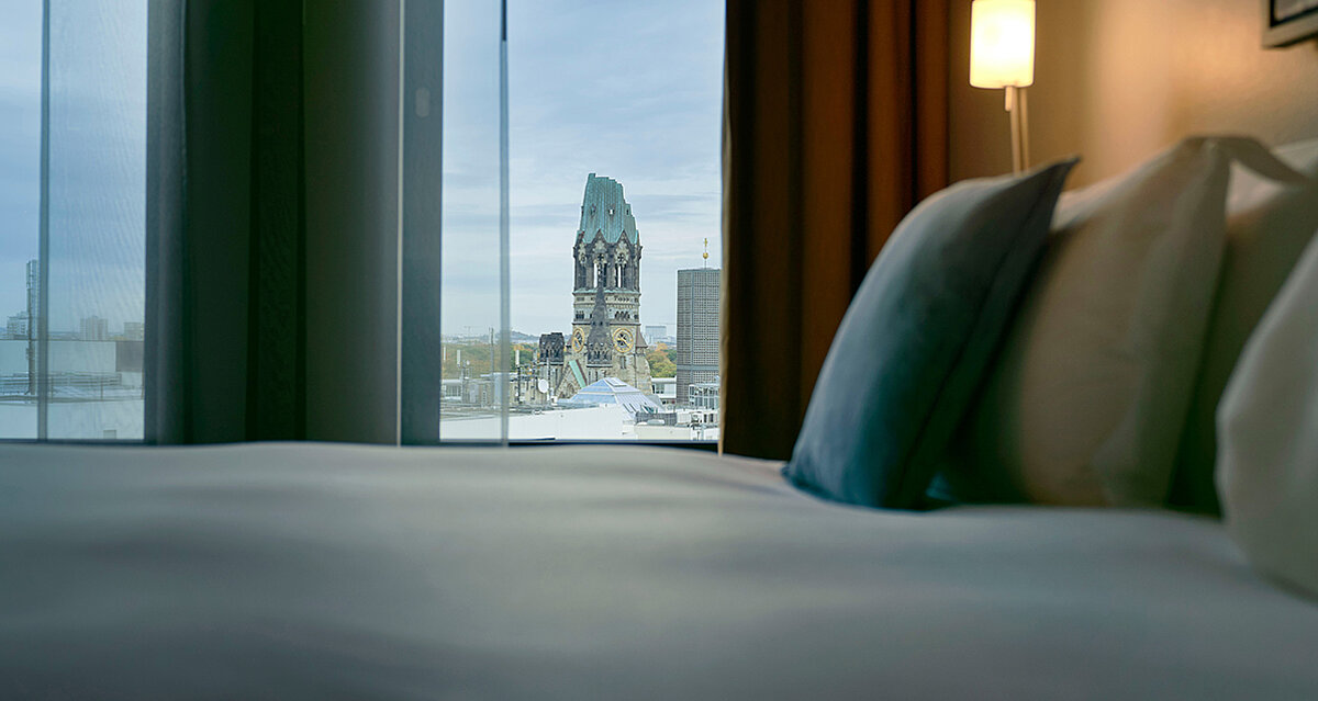 Langer gedeckter Tisch und ein Sektkühler mit drei Flaschen neben einem Gemälde im Hotel am Kurfürstendamm 