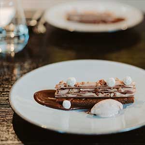 Das Bild zeigt ein elegantes, schokoladiges Dessert auf einem modernen Teller in einem gehobenen Restaurant.