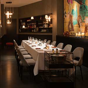 Das Bild zeigt einen eleganten, privaten Speisesaal mit einem langen Tisch, der für ein Abendessen gedeckt ist, und einer modernen, zurückhaltenden Atmosphäre.
